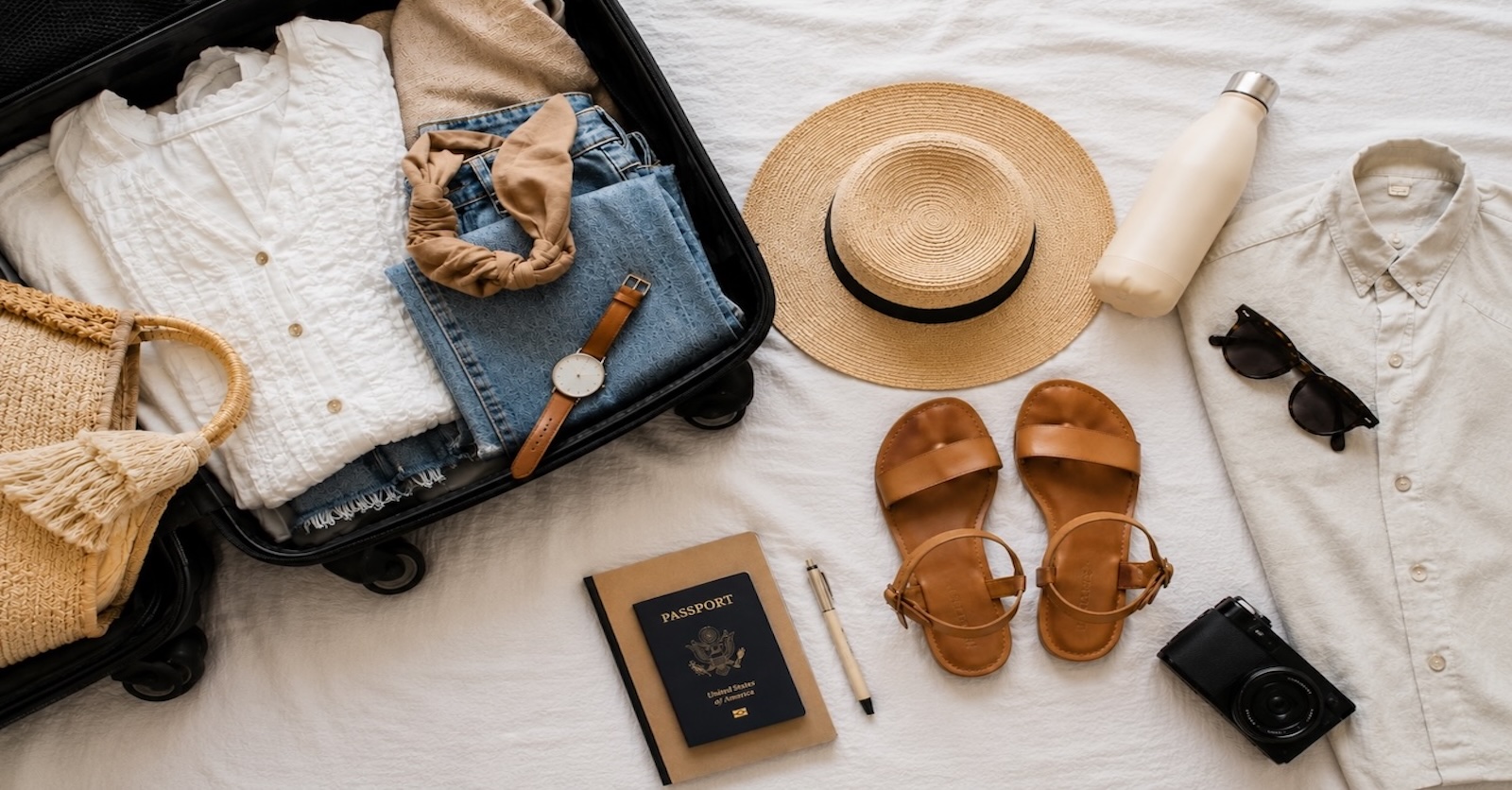 Open suitcase packed with summer clothes, sandals, hat and sunglasses for a hot weather holiday
