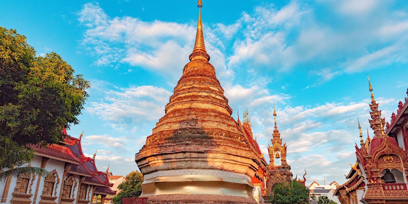 Golden-spired Chiang Mai temple and chedi under a blue sky at sunset